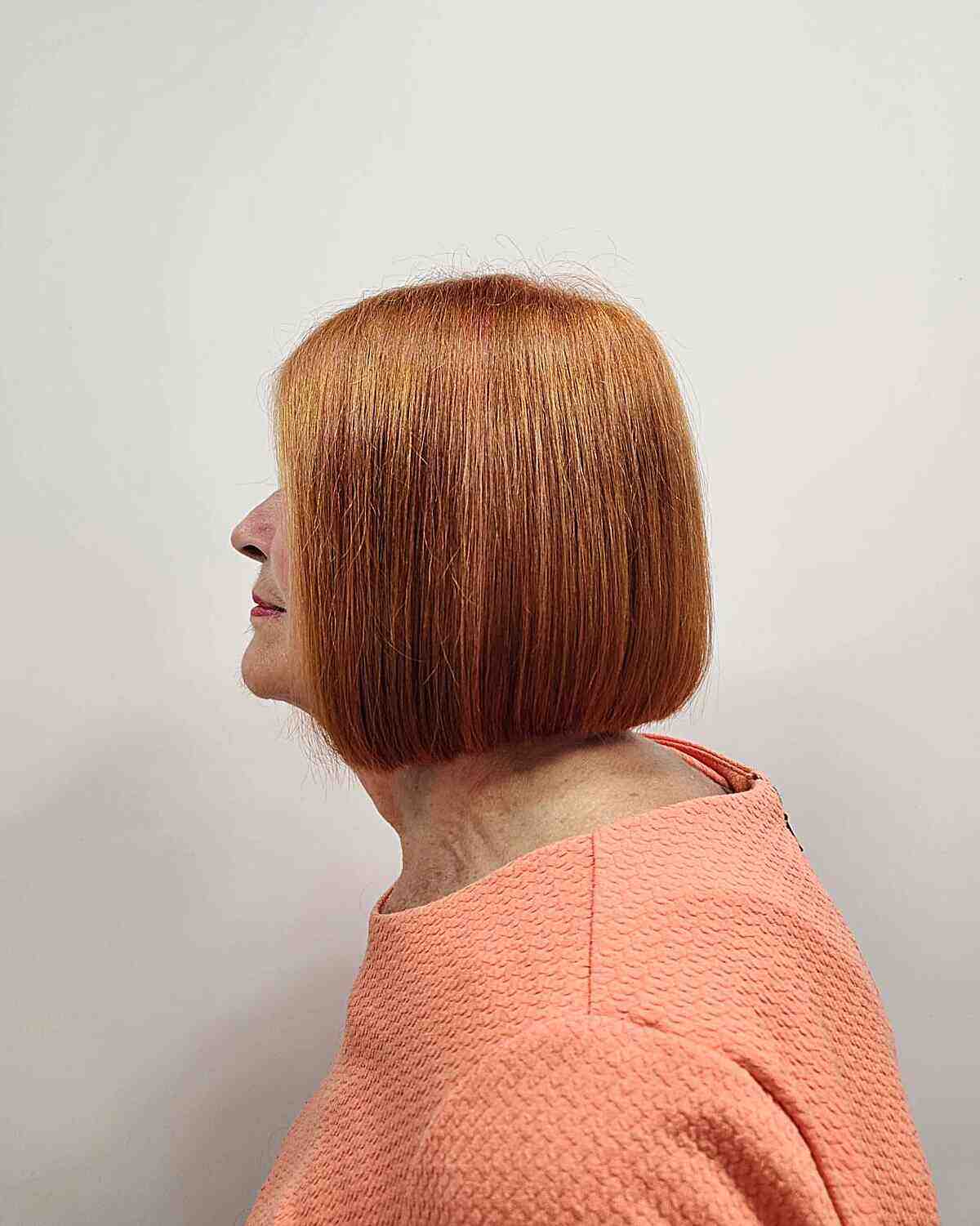 Um corte de cabelo curto em um estilo de outono com uma tonalidade vermelha natural para crianças de 60 anos