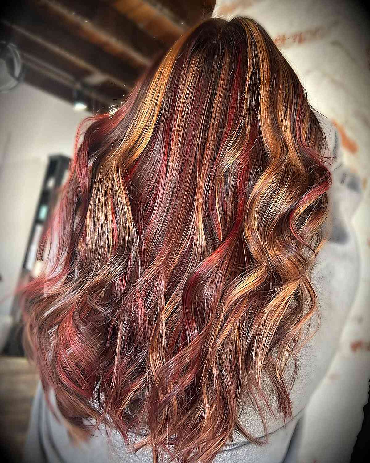 Detalhes vermelhos e brilhantes em cabelos castanhos longos